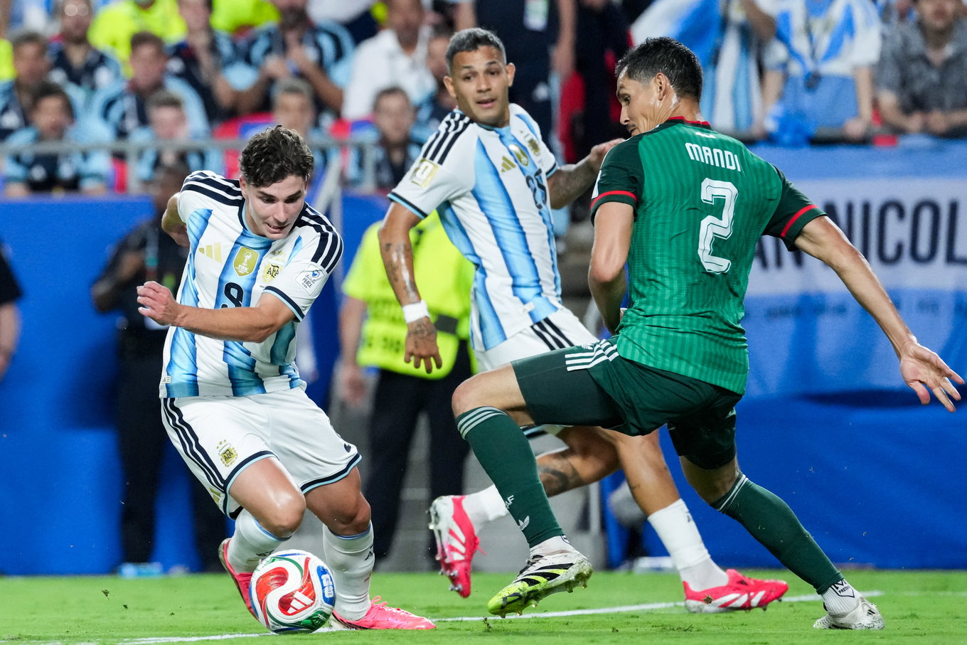 Julian Alvarez of Argentina (L) runs with the ball under pressure from Aissa Mandi of Algeria (R) during a FIFA M